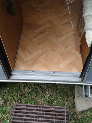 Seuil. Le trou du plancher en CP faisant face à la route et non traversant mesure 7cm x 5cm) se trouve à l'extémité gauche du seuil alu et presque totalement à cheval avec le côté du placard. On peut même dire que ce manque est dans le placard. Vraiment rien de méchant .A été arrangé depuis comme il faut.