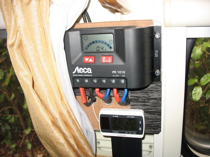 Régulateur entre les 2 fenêtres gauche: ici 0.4A reçu par le panneau à midi, il fait gris! <br />Jauge type carburant indiquant batterie "pleine";<br />à gauche: arrivée des 2 câbles solaires depuis le panneau, au milieu: câble à 2 conducteurs vers batterie, à droite: câble à 2 conducteurs vers prise-socle 13 broches.<br /><br />(dessous: thermomètre avec sonde fil blanc, dans frigo ou dehors passage par grille ou fenêtre)